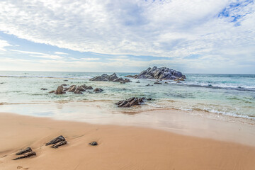 Sandy beach with rocks in the ocean.