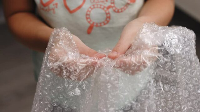 Baby girl playing with bubble wrap. Girl pressing the bubble wrapping replaces spinner, slime and pop it. Stress Calming the nervous system concept