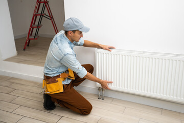 A man changes the heating in the house, radiators. The concept of modern heating, replacement of...