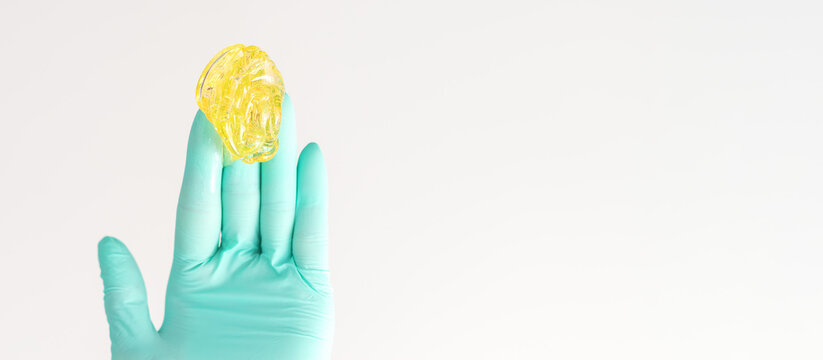 Yellow sugar paste in hand master of depilation. Smiling beautician holding wax for depilation over white background. Concept epilation