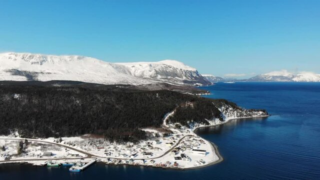 A coastal town backdropped by mountains in winter