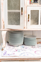 Vintage kitchen interior, wooden table and cutlery. White plates standing at each other. Stock photo