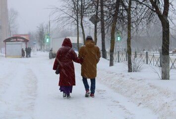 Man and woman walking in snowfall at snowy city street
