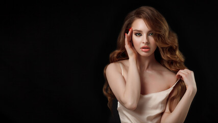 Naklejka premium Beauty portrait of elegant young woman. Glamour makeup. Face of the beautiful woman with long brown curly hair posing at studio over dark background. Sensual portrait.
