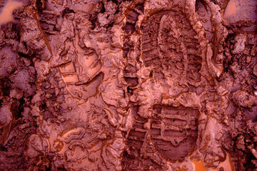 A boot print in the mud close-up. Footprint in the dirt. Bottom of shoes.