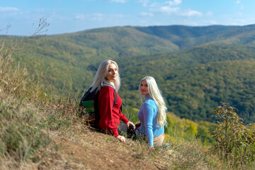 Fototapeta na wymiar Two beautiful blonde woman walking in the mountain during a sunny day