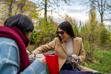 Two beautiful young women with shopping bags sitting on a bench