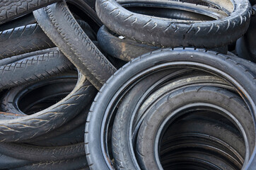 Old discard black motoecycle tire heap in light