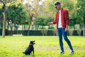 Man in sunglasses playing with a dog and stick