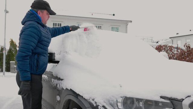 Close up view of man cleaning windshield from snow. Vehicle concept background. Sweden.