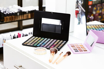 Palette of shadows, brushes and professional makeup on table with vanity lighting. Horizontal photo.