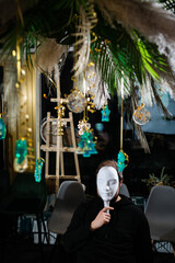 Portrait of man at table wearing mafia mask surrounded by Christmas decoration