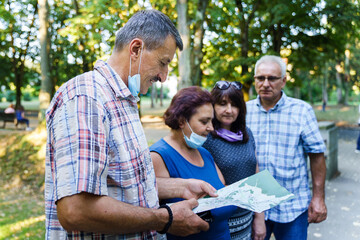 Group of senior friends tourists in autumn or summer day - Mature man showing to his wife and...