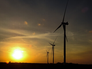 Huge Wind Power Turbines Silhouetted by a Sunset on the Horizon