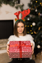 The young girl gives a red Christmas gift on a camera
