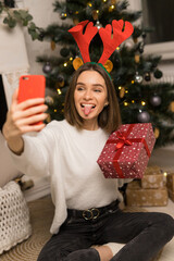 Close up of young girl telephone to parents and show a red Christmas gift and her tongue