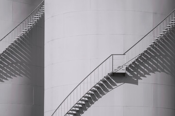 Sunlight and shadow on spiral staircases surface of 2 oil storage fuel tanks in monochrome style