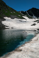 snowy coast and clear blue mountain lake in Arkhyz