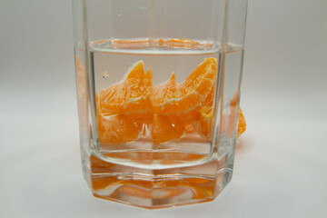 Peeled tangerine slices in a glass of water