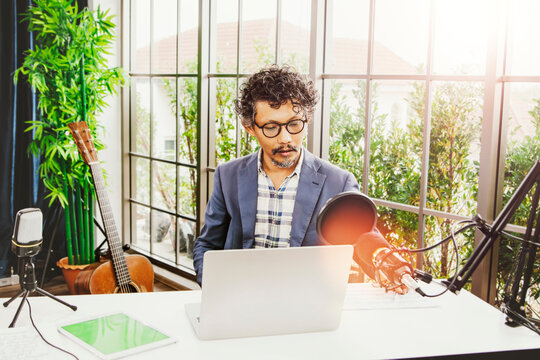 Professional male classical guitar teacher tutor sitting in music room talking to students on video call online course : Online education concept.