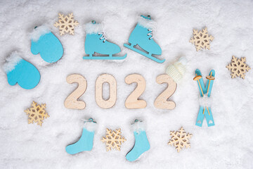 Sports year 2022. Sports set with bright blue wooden skates, skis, sledges, snowflakes and date...
