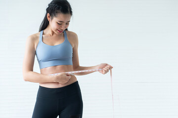 Pretty girl wearing sportswear using measurement tape on white background, healthy lifestyle concept