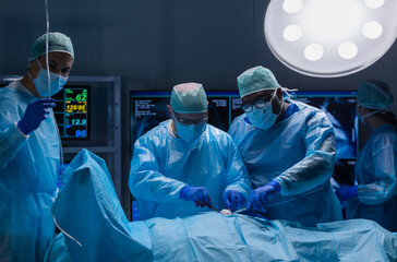 Multiracial team of professional medical surgeons performs the surgical operation in a modern...