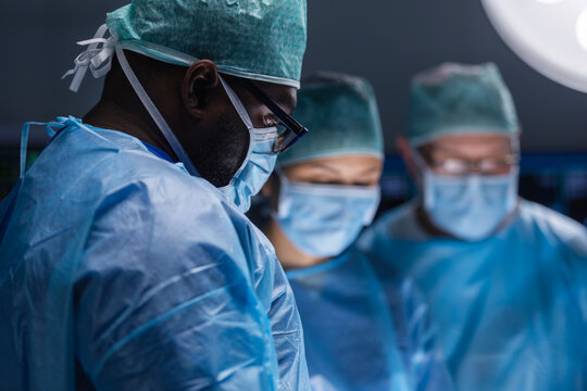 Multiracial team of professional medical surgeons performs the surgical operation in a modern hospital. Doctors are working to save the patient. Medicine, health, cardiology and transplantation.