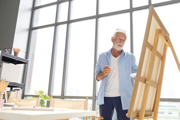 senior man painting a picture from paintbrush in free time