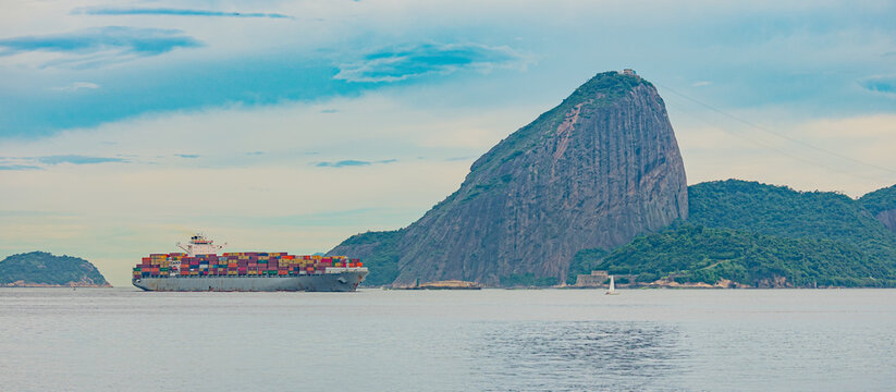 Rio de Janeiro, Brazil - December, 2021: Photo of Sugarloaf Mountain, Pão de Açúcar, with a cargo ship passing in front of it in Guanabara Bay during the day