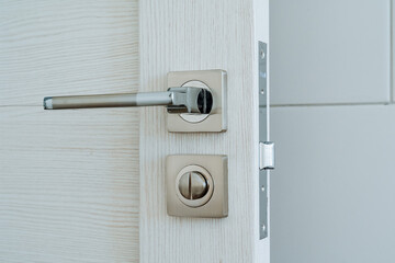 Metal door handle. White wooden door in a modern interior. Entrance to the room. Minimalistic interior of the house