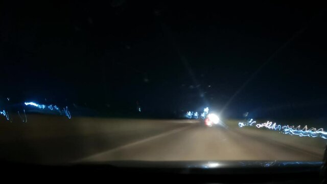 4K Hyper lapse of the highway at night as seen from inside the car  with dirty windshield. POV from inside the car. Cars leaving light trails. Travel Background. High speed motion of the car at Night