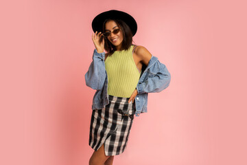 Nice smiling stylish woman in spring outfit posing over pink backgrond in studio.