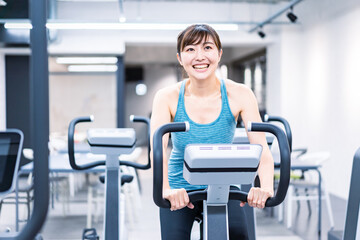 Fototapeta premium ジムでマシーントレーニングをする若い女性