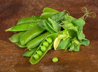 Green peas with leaves on wooden background