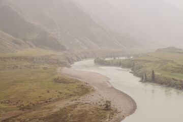 Vintage misty mountain landscape with wide mountain river in sepia tones. Dark gloomy scenery with big mountain river in mist. Dark atmospheric view to great river among big mountains in faded colors.