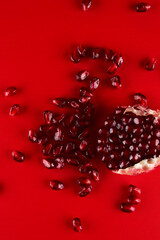 Ruby ripe fresh juicy pomegranate seeds close up isolated on red background