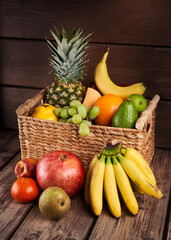 Mix of fresh juicy colorful exotic tropical fruits in basket on wooden background