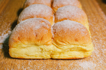 White bread buns with fluffy filling, sprinkled with sugar, on a wooden tray,bakery,close-up.