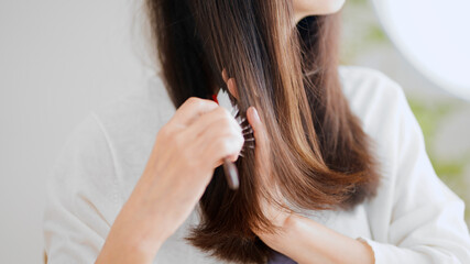 髪にブラシをかけるシニア女性