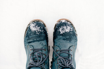 Closeup photo of winter symmetrically put blue warm boots with laces out in snow making footprint on ground covered with snow. Astonishing background full of white and show. 