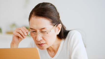 老眼鏡でノートパソコンを覗くシニア女性