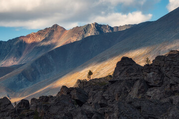 Dark contrasting mountains at sunset. Evening mountain landscape with rock in golden sunlight....