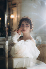 Naklejka premium Beautiful curly-haired bride in a luxury wedding dress in a restaurant with wedding decor