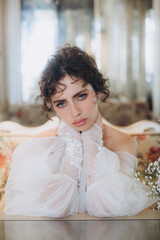 Fototapeta premium Beautiful curly-haired bride in a luxury wedding dress in a restaurant with wedding decor