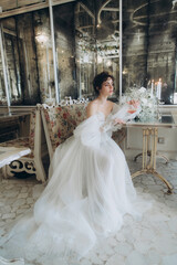 Beautiful curly-haired bride in a luxury wedding dress in a restaurant with wedding decor