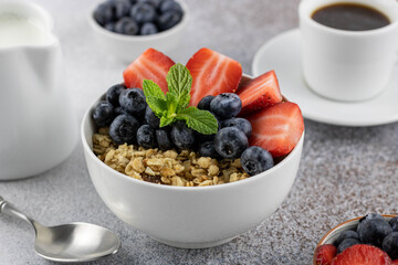 Healthy breakfast: granola with strawberries, blueberries, milk and freshly brewed coffee