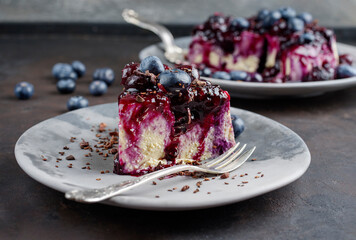 Traditional blueberry cheesecake with fresh berries, compote and chocolate crumbles served as close-up on a design plate with copy space