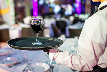 Waiter holding tray with red wine glass