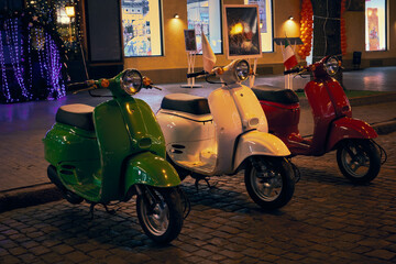Fototapeta na wymiar Photo the gree, red and white vintage Italian Motorcycles on st. Deribasovskaya at winter evening in Odessa Ukraine